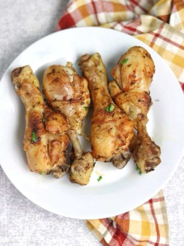 4 baked chicken drumsticks on a white plate.