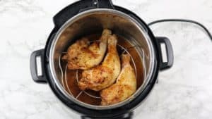 Browned chicken arranged on trivet in the instant pot.