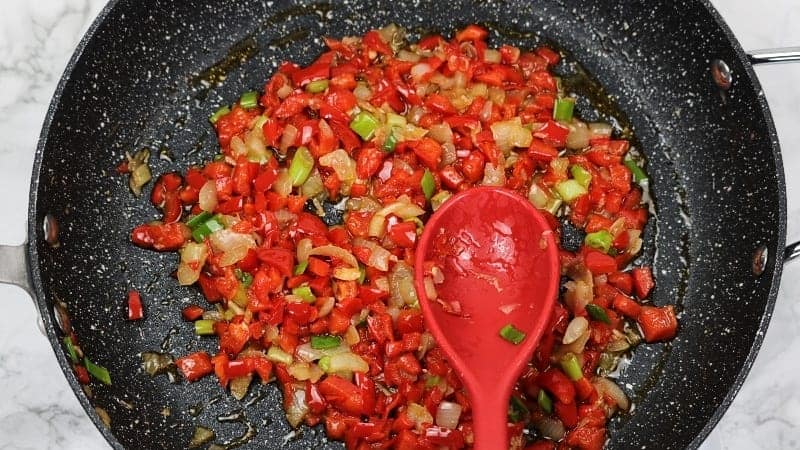 onions and peppers sauteed in pan.
