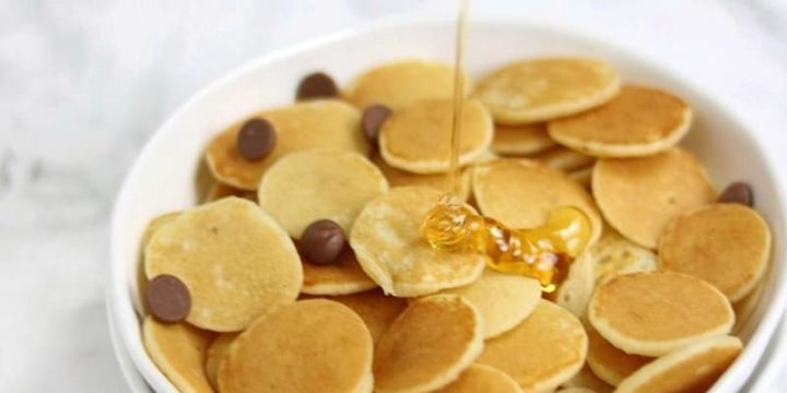 mini pancakes in a white bowl with syrup drip.