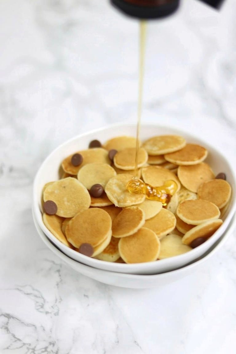 mini pancakes in a white bowl with syrup drip.